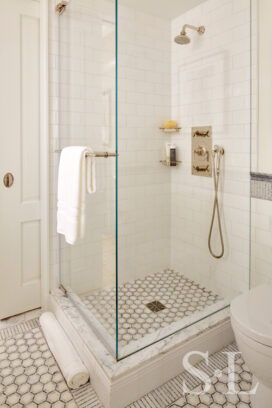 White and grey bathroom, view into shower with nickel hardware