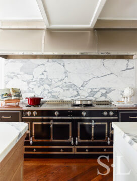 Chicago penthouse kitchen view of black and polished chrome range by La Cornue and custom stainless steel hood