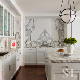 Chicago penthouse kitchen view of large prep-island and statuary marble wallscape