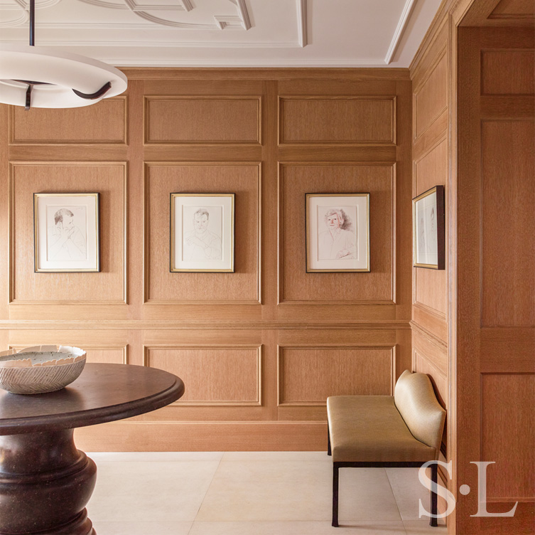 Chicago penthouse entry foyer with cerused oak paneled millwork, a collection of artwork by David Hockney, an iron and plaster pendant light and a Belgian bluestone table