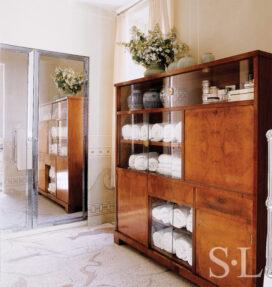 Deco-era duplex apartment bathroom detail showing large wood and glass storage cabinet