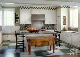 Restored landmark residence on former military base kitchen with green-and-white painted checkerboard floor and antique Irish butcher block table