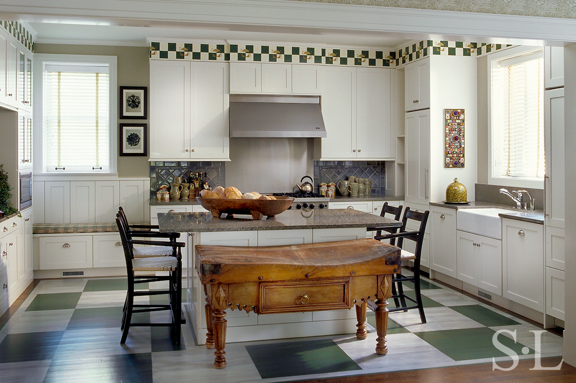 Restored landmark residence on former military base kitchen with green-and-white painted checkerboard floor and antique Irish butcher block table