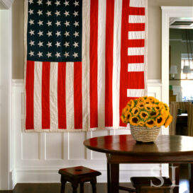 Restored landmark residence on former military base stair hall with table and chairs and a 1930’s “American Flag” quilt with improvised design