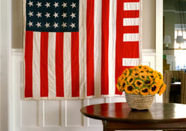 Restored landmark residence on former military base stair hall with table and chairs and a 1930’s “American Flag” quilt with improvised design