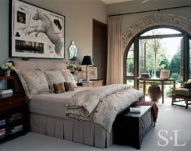 Former artillery shed converted into luxury residence bedroom with Chinese Demilune table in front of open arched doorway and artwork by Joseph Piccillo