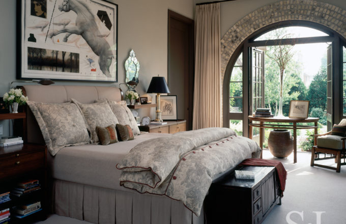 Former artillery shed converted into luxury residence bedroom with Chinese Demilune table in front of open arched doorway and artwork by Joseph Piccillo