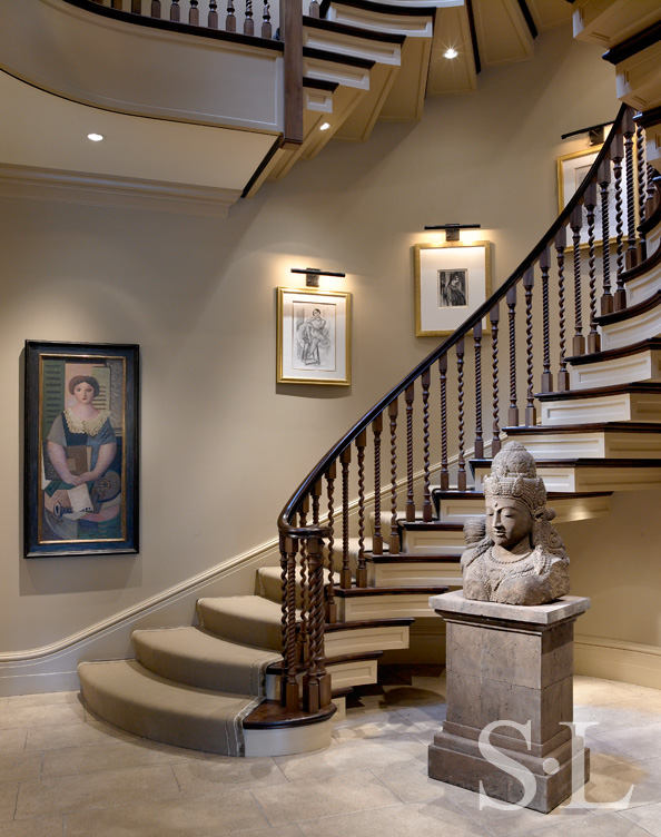 Stairway in Lincoln Park residence lined with portraits and a bust of Shiva at the base
