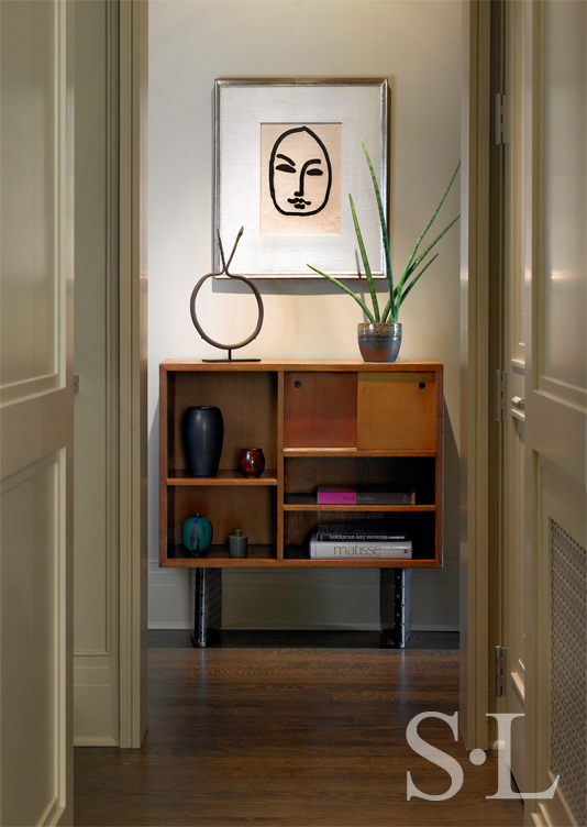 Chicago high-rise apartment hallway showing a Matisse hanging above a mid-century cabinet by Le Corbusier and Charlotte Perriand