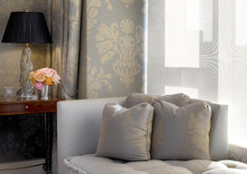 Chicago apartment bedroom with damask upholstered walls and drapery, and chaise in front of window