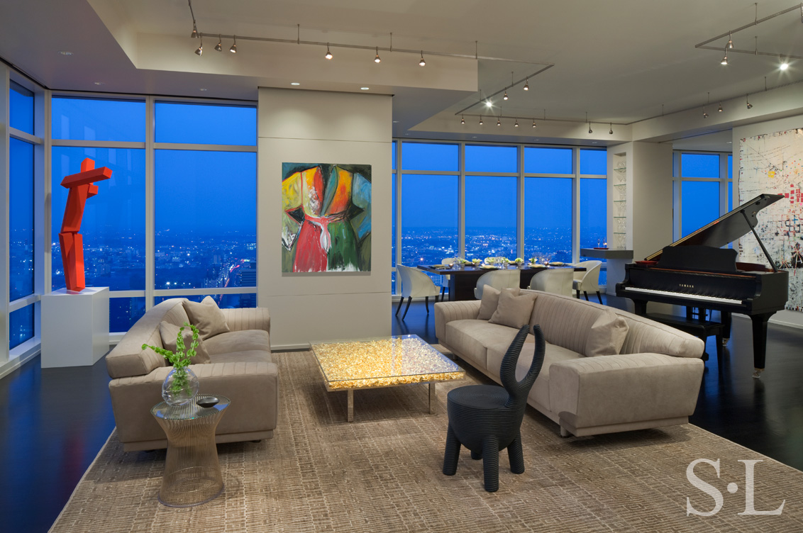Manhattan residence living room at dusk with sweeping views of New York, featuring a painting by Jim Dine and a coffee table by Yves Kline