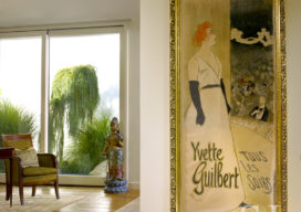 Master bedroom detail with large artwork by Toulouse-Lautrec, seating and a view of exterior landscaping