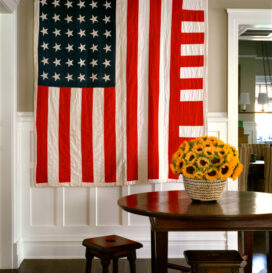 Restored landmark residence on former military base stair hall with table and chairs and a 1930’s “American Flag” quilt with improvised design