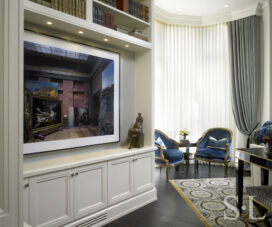 A lighted millwork alcove with artwork by Robert Polidori, two Bergere chairs in black lacquer and gold details and antique Eastern European carpet in the living room of this waterfront townhome