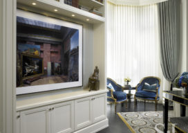 A lighted millwork alcove with artwork by Robert Polidori, two Bergere chairs in black lacquer and gold details and antique Eastern European carpet in the living room of this waterfront townhome