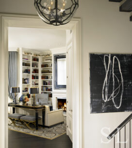 View from foyer into living room of waterfront townhome featuring a console table in black lacquer, wing-back chairs, and an art moderne-style mirror all custom designed by Suzanne Lovell Inc.