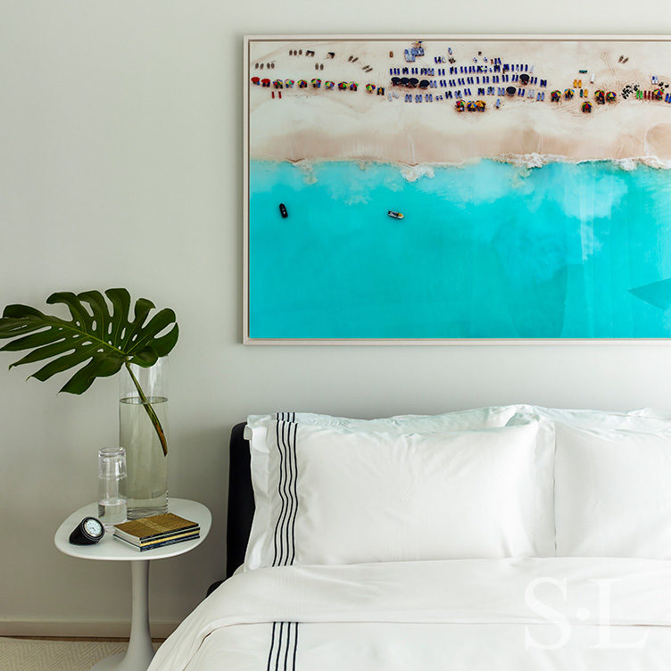 Guest bedroom detail with beach artwork above bed