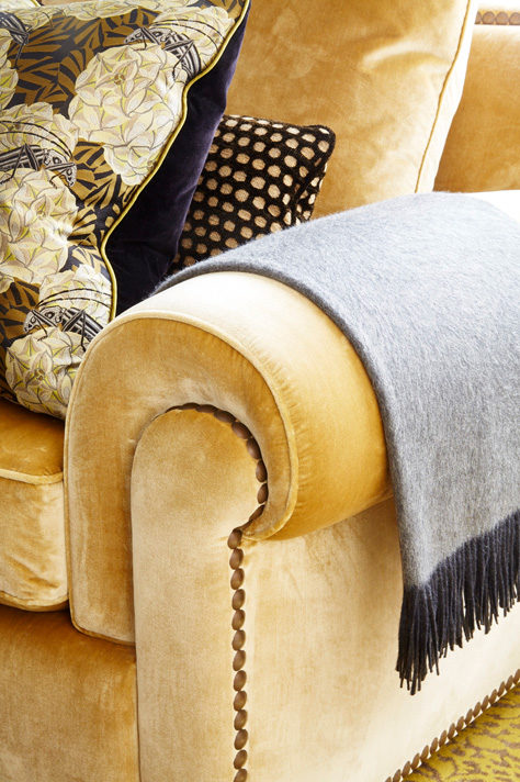 Detail of custom Chanel sofa upholstered in deluxe silk velvet with grey throw blanket and pillows