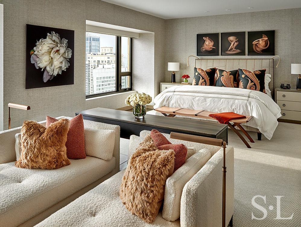 Chicago luxury apartment bedroom in warm neutral tones showing seating area and bed