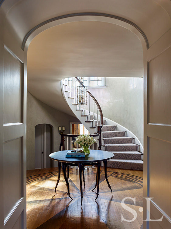 Scarsdale, NY residence entry foyer renovation with Michael Wilson table, curved staircase and Paul Ferrante pendant light fixture