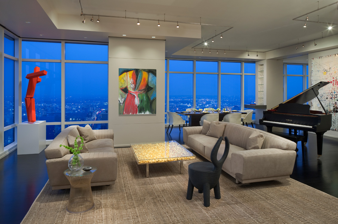 Manhattan residence living room at dusk with sweeping views of New York, featuring a painting by Jim Dine and a coffee table by Yves Kline