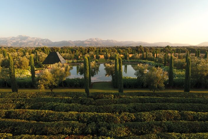 A garden in Majorca by landscape designer Fernando Caruncho featuring clipped ridges and a pool with a pavilion