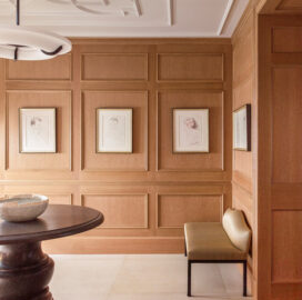 Chicago penthouse entry foyer with cerused oak paneled millwork, a collection of artwork by David Hockney, an iron and plaster pendant light and a Belgian bluestone table