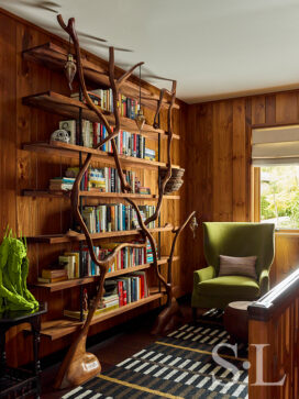 Lakeside residence hallway detail with sculptural tree bookshelf and rustic interior design touches