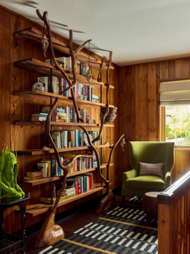 Lakeside residence hallway detail with sculptural tree bookshelf and rustic interior design touches